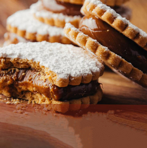 Delicate shortbread cookies filled with ceamy dulce de leche caramel and dusted in white powdered sugar.